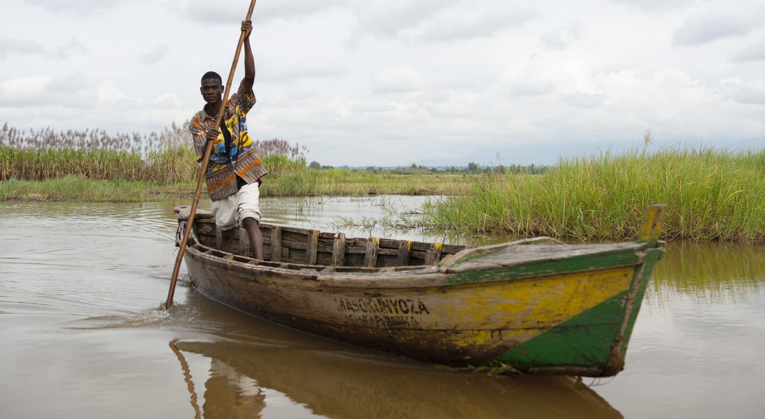 A man poling a wooden boat.