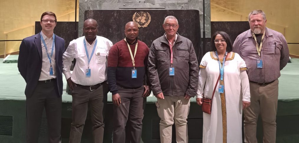 Six people posing in front of the UN emblem.