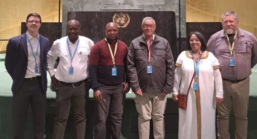 Six people posing in front of the UN emblem.