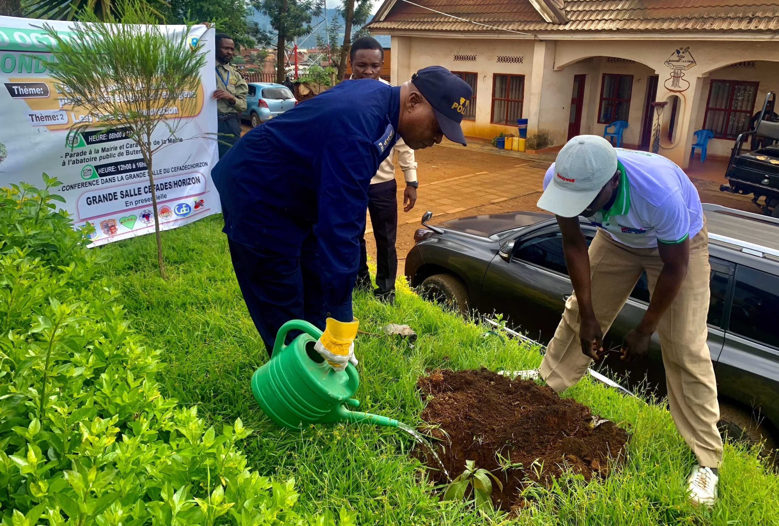 A policeman waters a newly planted plant.