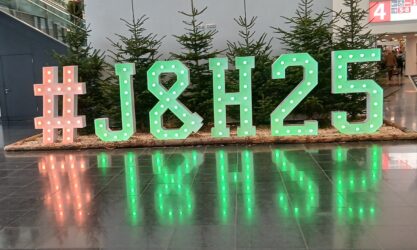 A green sign picked out in lights of the hashtag #J&H25