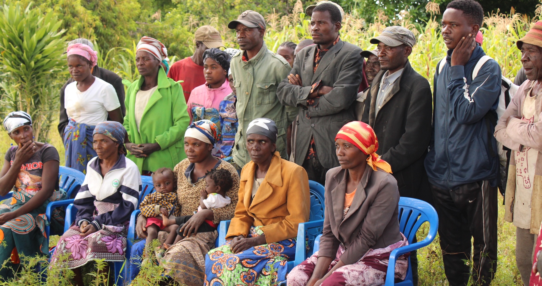 A group of community members sit and stand looking surprised.