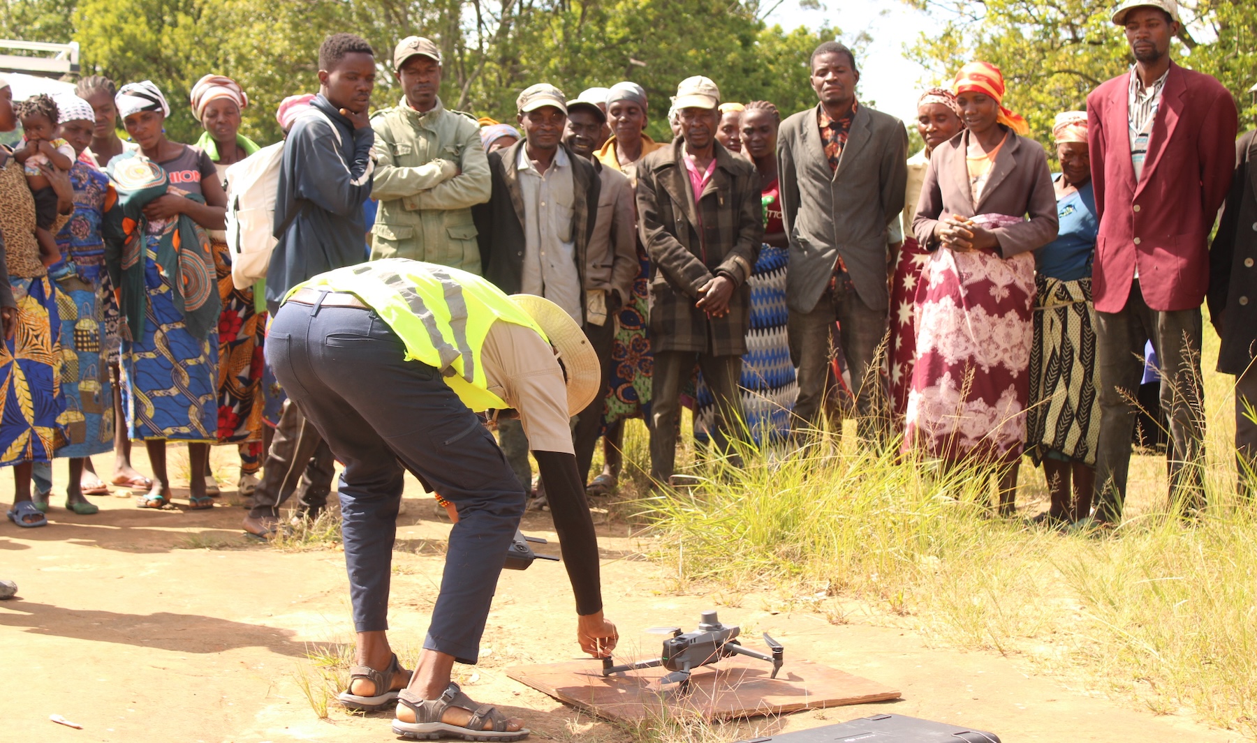 A group of community members watch as a drone is prepped for take-off.